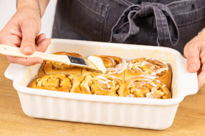 Apfel-Zimtschnecken mit Frosting bestreichen