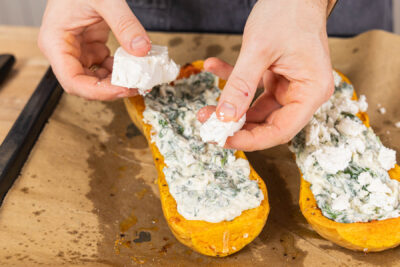 Feta über den Kürbis bröseln, für gefüllter Butternut-Kürbis mit Spinat und Feta