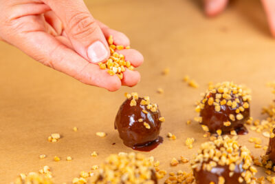 Käsekuchen-Kugeln mit Krokant bestreuen