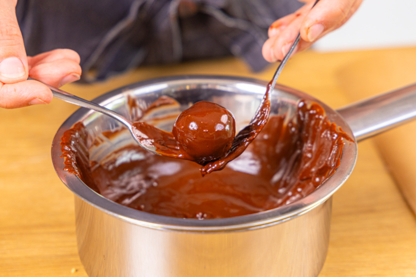 Käsekuchen-Kugeln in dunkler Schokolade wälzen