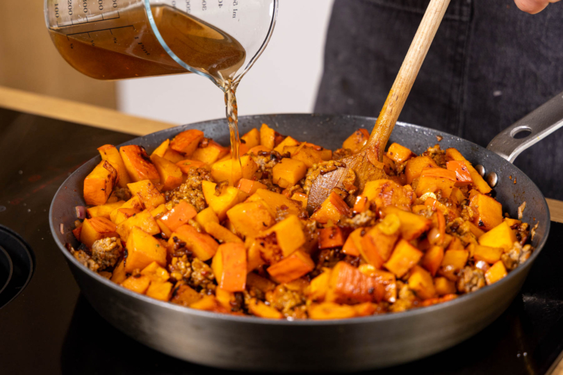 Gemüsebrühe zur Kürbis-Hackfleisch-Pfanne gießen