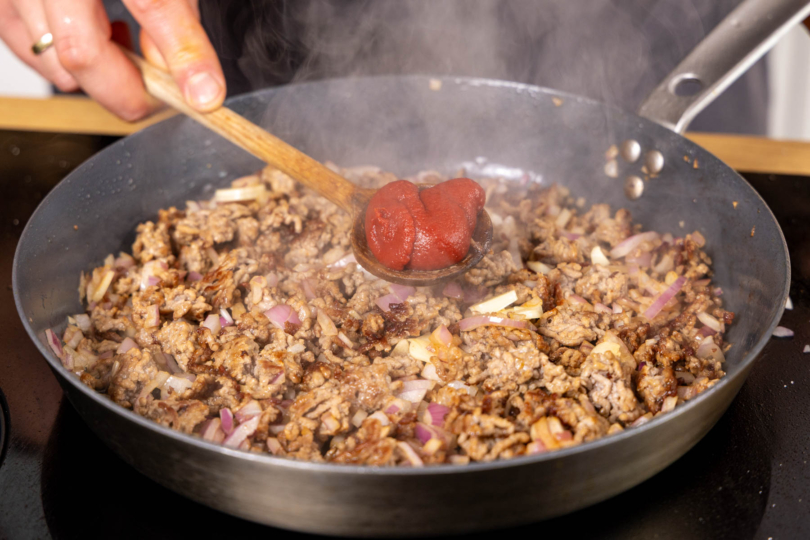 Tomatenmark zum Hackfleisch geben