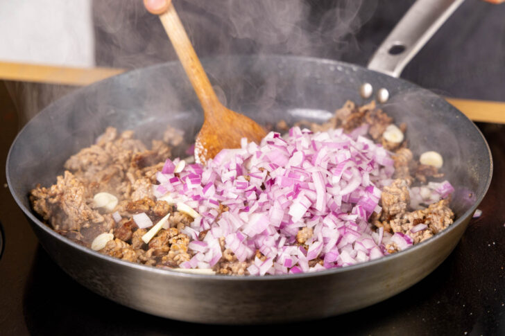Zwiebel und Knoblauch zum Hack geben