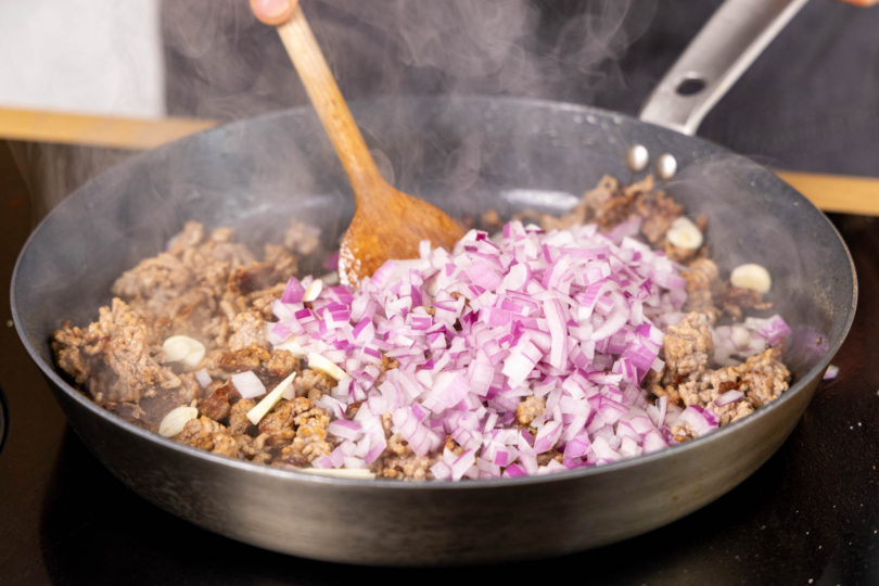 Zwiebel und Knoblauch zum Hack geben