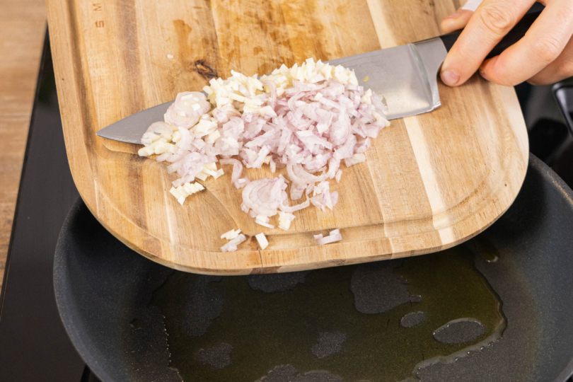 Schalotten und Knoblauch in die Pfanne geben