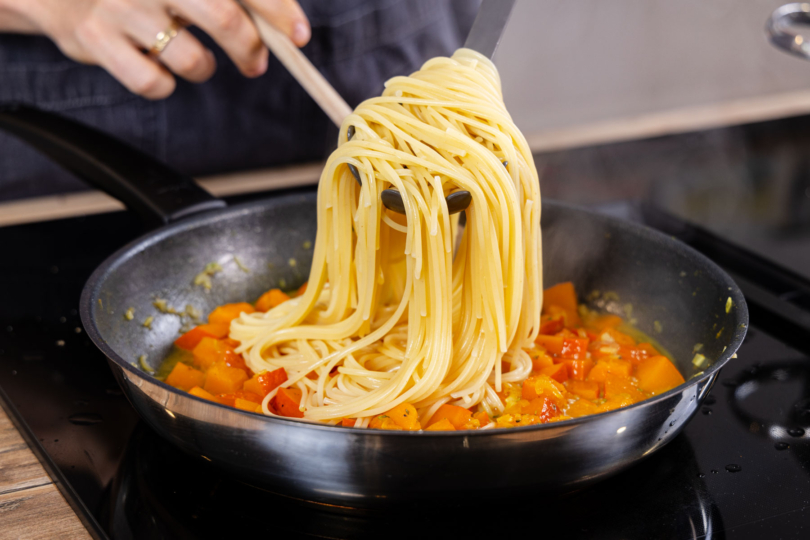 Spaghetti in die Pfanne geben