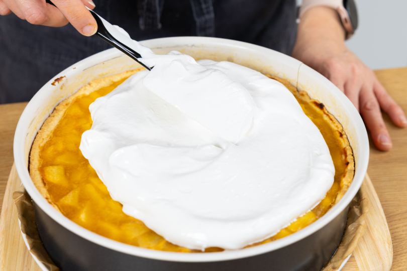 Baisermasse auf dem Quittenkuchen verteilen