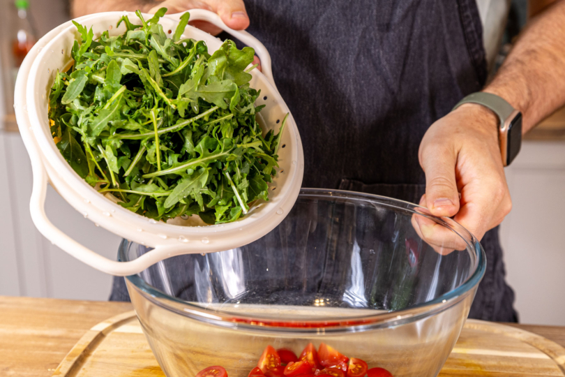 Rucola in die Schüssel geben