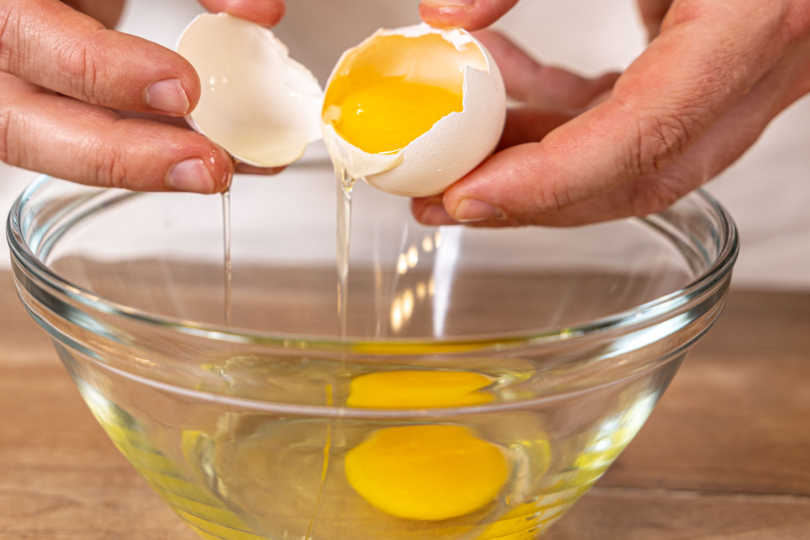 Eier in eine Schüssel schlagen