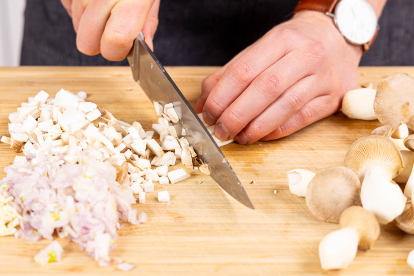 Schalotten, Knoblauch und Kräuterseitlinge in kleine Würfel schneiden