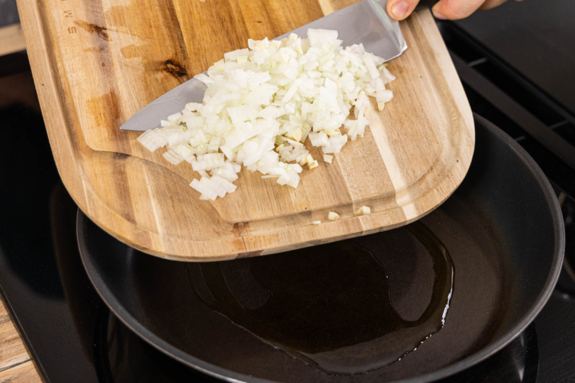 Zwiebelwürfel in die Pfanne geben