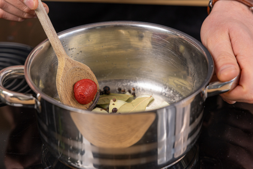 Tomatenmark und Gewürze in den Topf geben