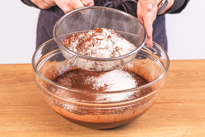 Mehl und Backkakao zum Teig sieben