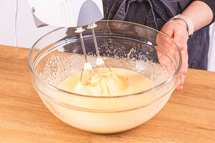 Zucker und Eier mit Handrührgerät verrühren