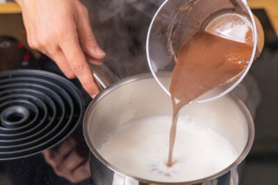 angerührtes Puddingpulver zur Milch in den Topf geben