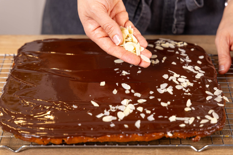 Honigkuchen vom Blech mit Schokoglasur und Mandeln dekorieren