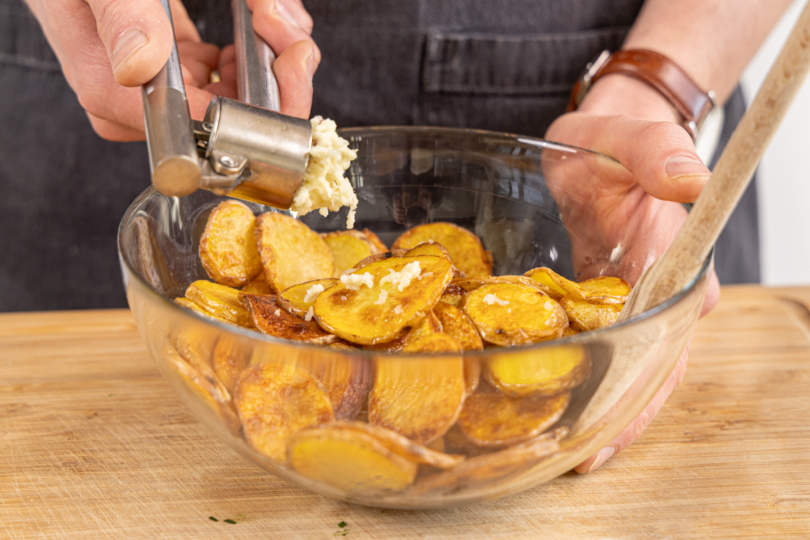 Knoblauch zu den gebratenen Kartoffelscheiben geben
