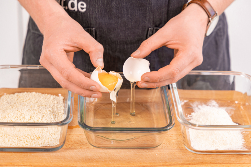 Ei in eine Schüssel schlagen