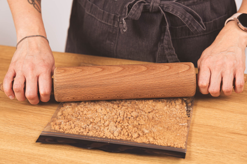 Spekulatius in Tüte mit Nudelholz zerbröseln