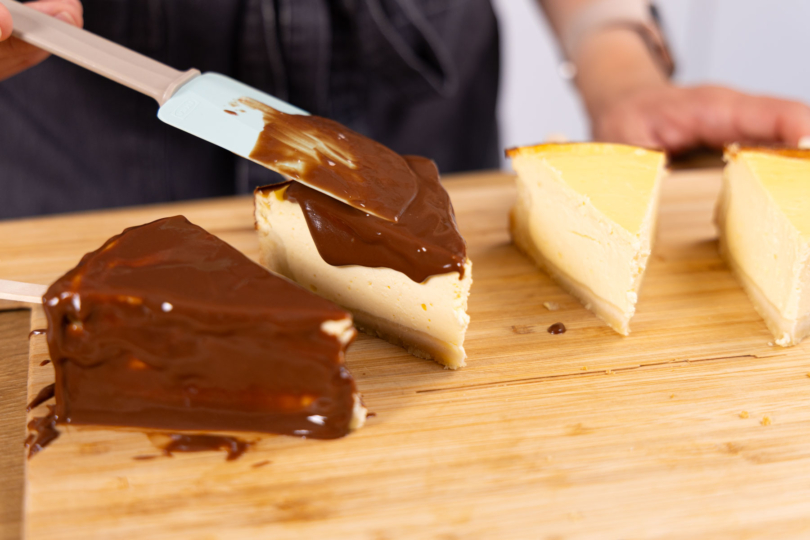 Cheesecake-Sticks mit brauner Kuvertüre verzieren.