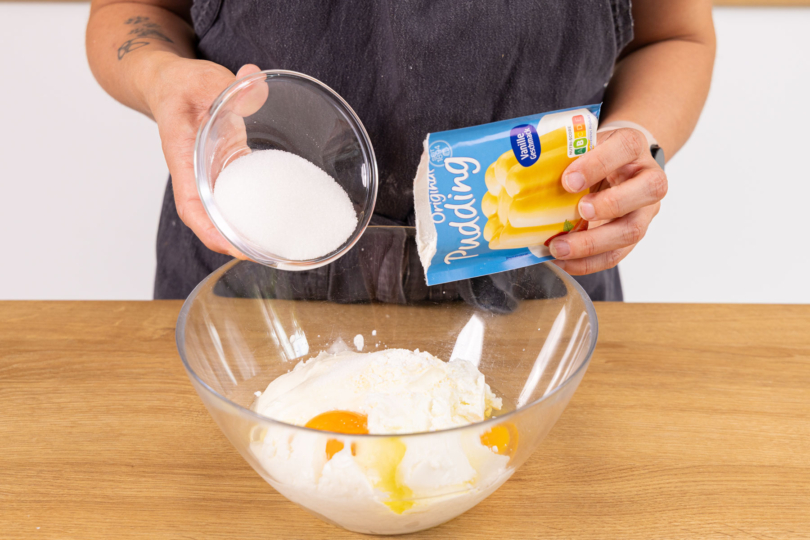 Puddingpulver und Zucker zu Cheesecakemasse geben.