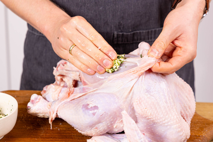 Kräuterbutter zwischen Haut und Fleisch verteilen