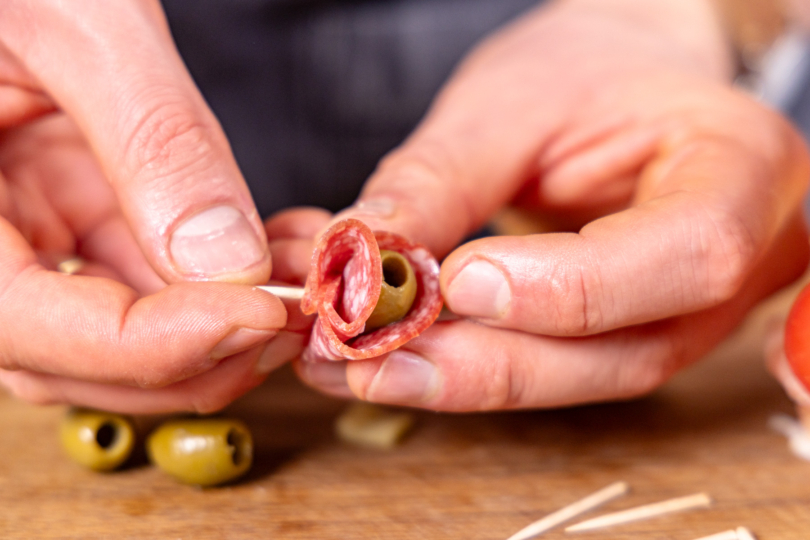 Salami um eine Olive wickeln