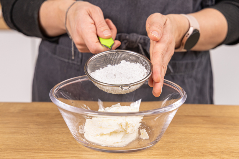 Puderzucker in die Schüssel sieben