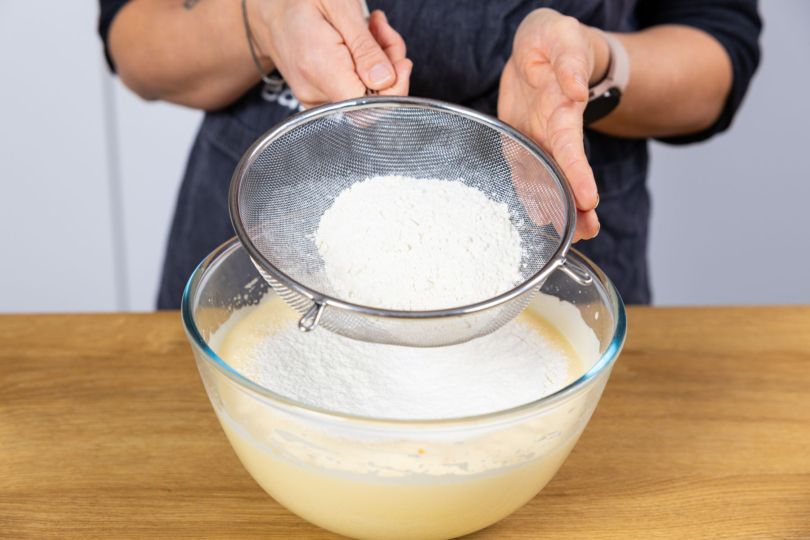 Mehl in Teig sieben.