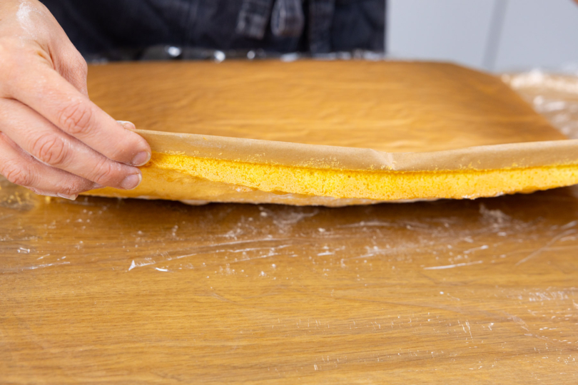 Biskuitteig umdrehen und das Backpapier entfernen.