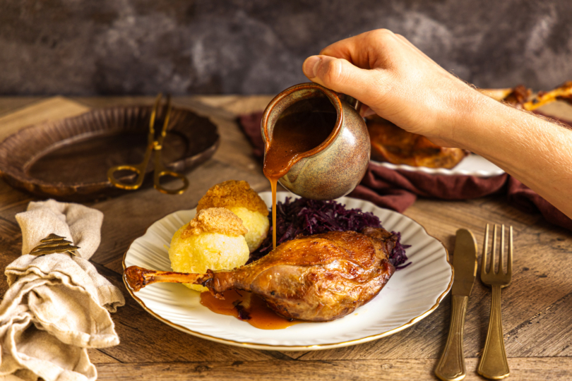 Geschmorte Gänsekeulen mit Soße anrichten