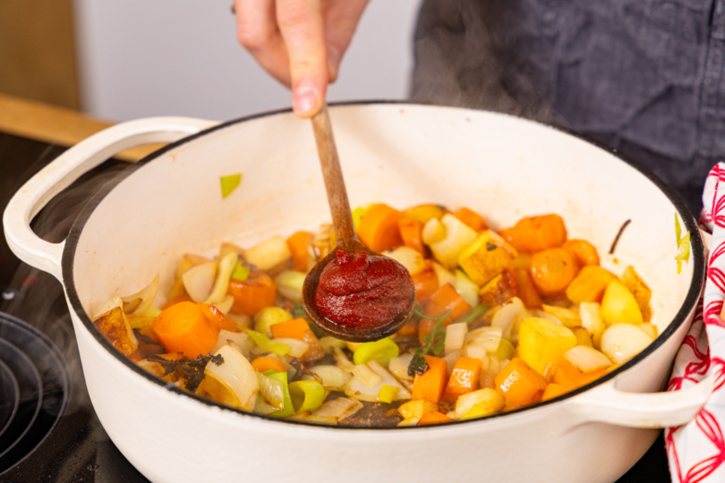 Tomatenmark zum gebratenen Gemüse geben