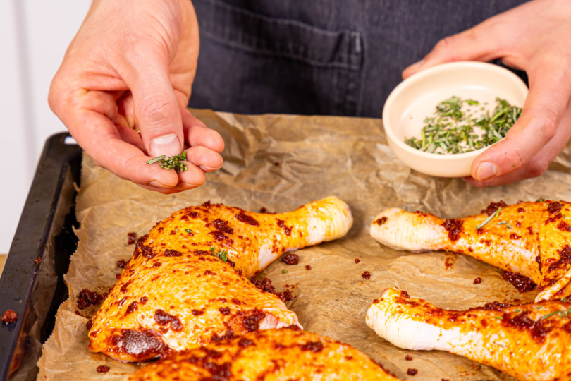 gehackten Rosmarin über die Hähnchenkeulen streuen