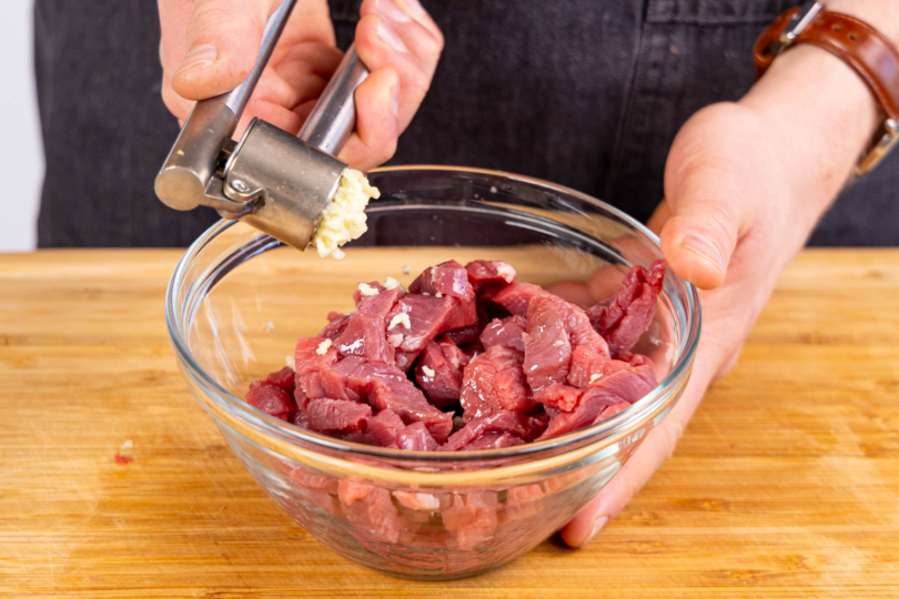 Knoblauch schälen und zum Fleisch pressen