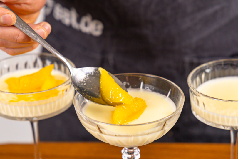 Orangensoße über Panna COtta geben