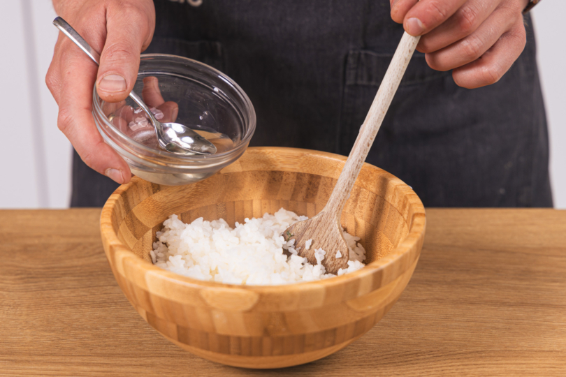 Sushi-Reis mit der Zucker-Essig-Mischung übergießen