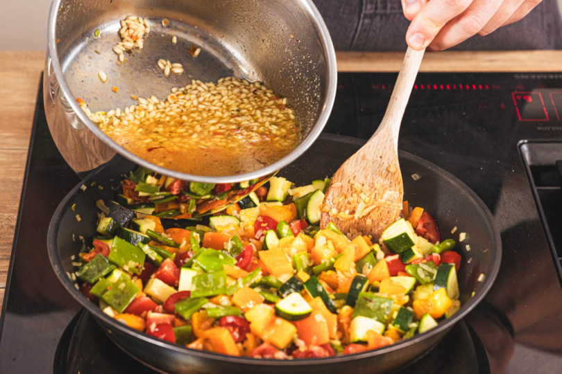 Reis mit Brühe zur Paella geben