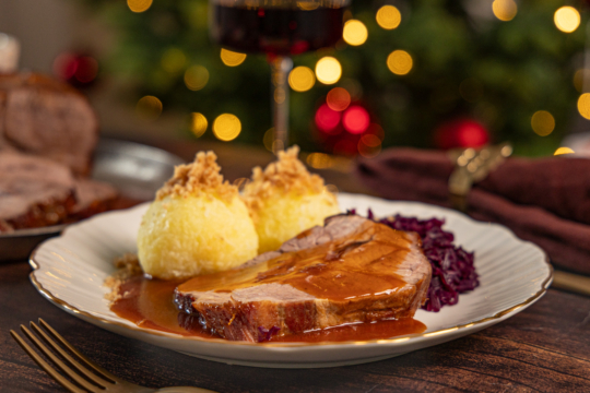Weihnachtsbraten vom Schwein auf dem Teller mit Klößen und Rotkohl