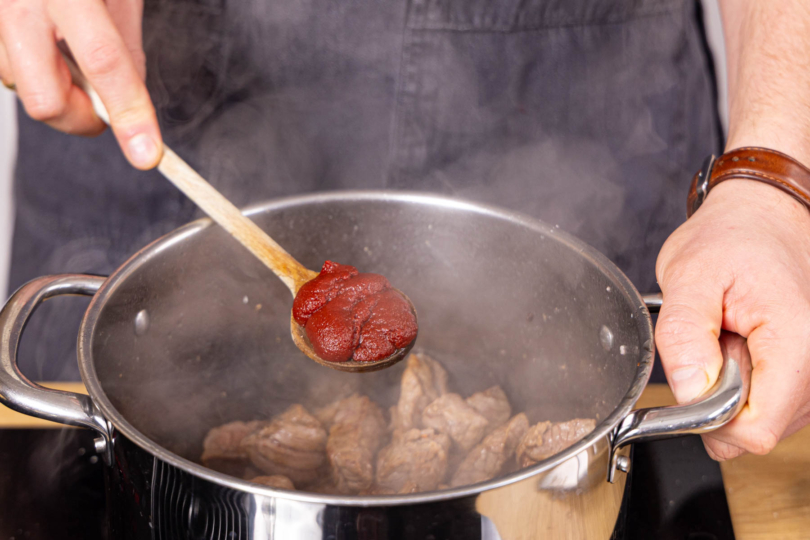 Gewürze und Tomatenmark dazugeben