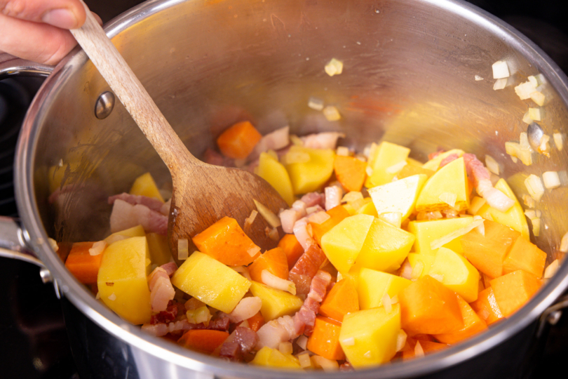 Gemüse zum Speck in den Topf geben
