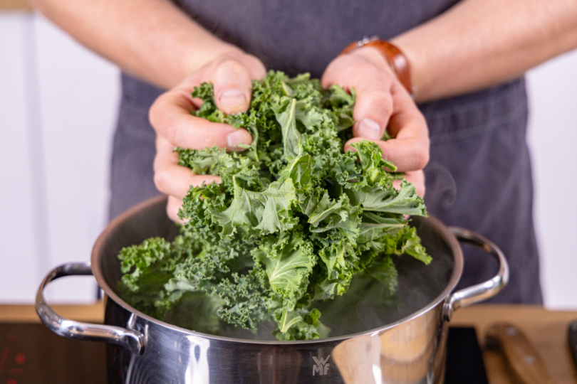 Grünkohl in den Topf geben