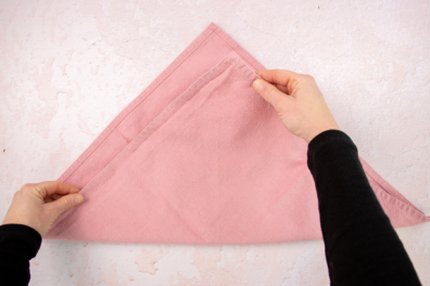 Stoffserviette zum Dreieck falten als Vorbereitung zum Herz falten