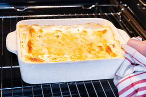 Kartoffelgratin aus dem Ofen holen