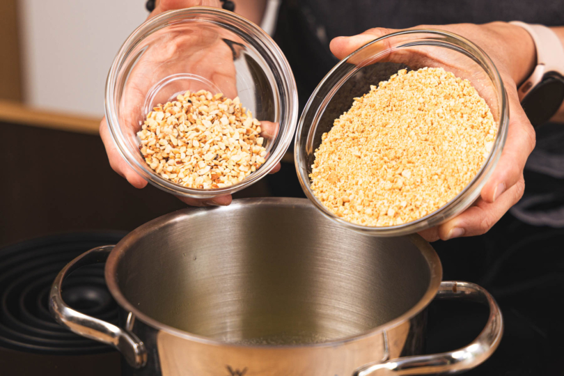 Keksbrösel und gehackte Nüsse zur Butter in den Topf geben