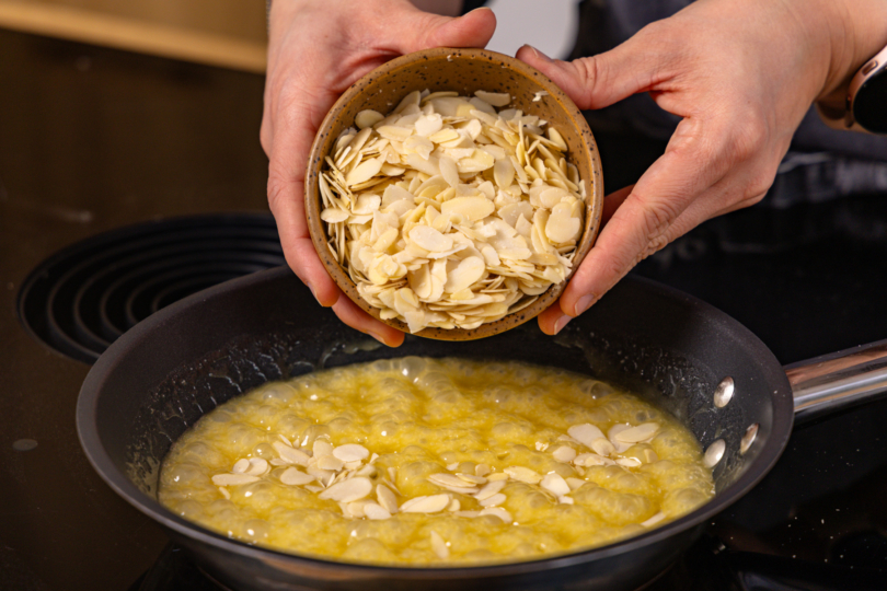 gehoblete Mandlen in geschmolzene Butter-Zucker-Honig-Mischung geben