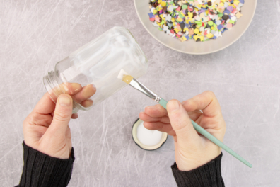 Einwegglas mit Bastelkleber bestreichen