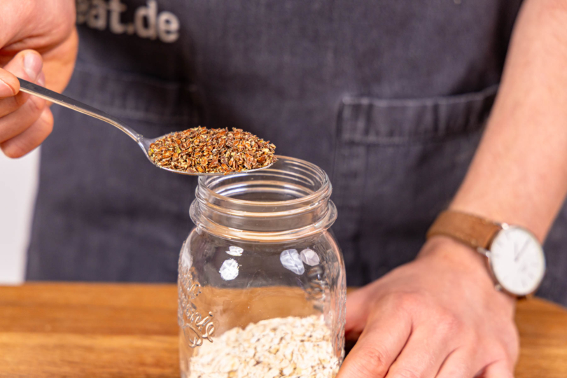Haferflocken und Leinsamen in ein Schraubglas geben