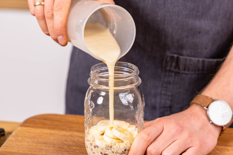 pürierte Banane mit Hafermilch ins Glas gießen