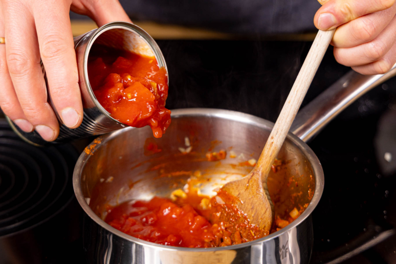 gehackte Tomaten dazugeben undravas-Sauce einköcheln lassen