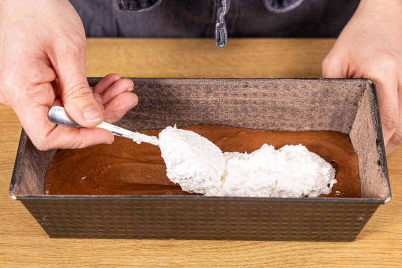 Kokosmasse als länglicher Kern auf dem Schokoteig verteilen